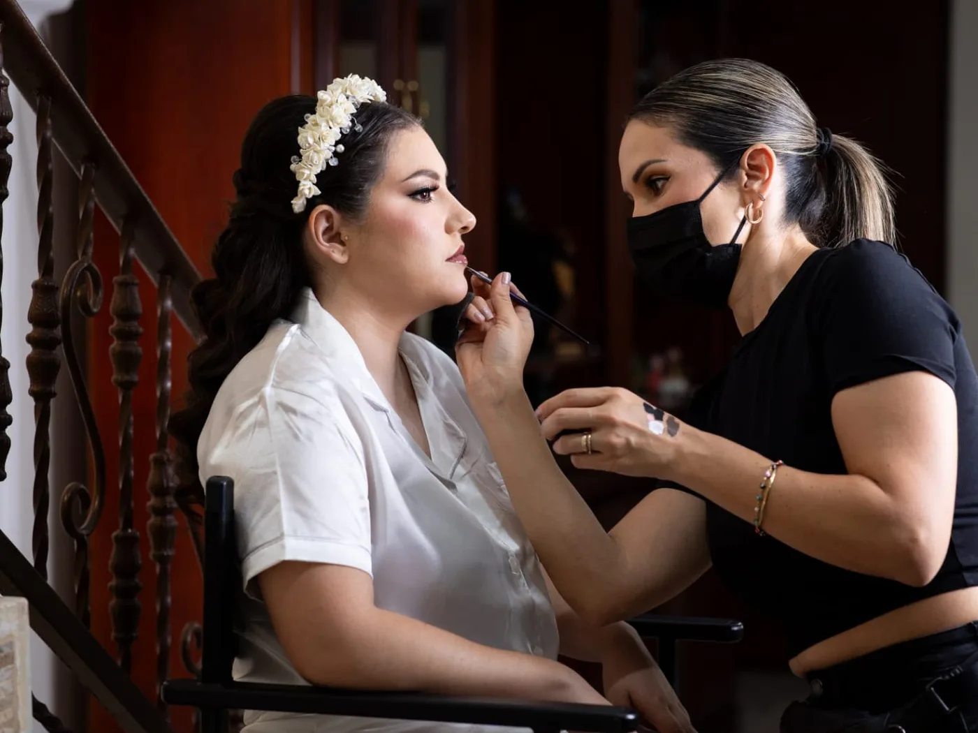 Janette Fonseca aplicando labial con pincel a una novia con tocado de flores
