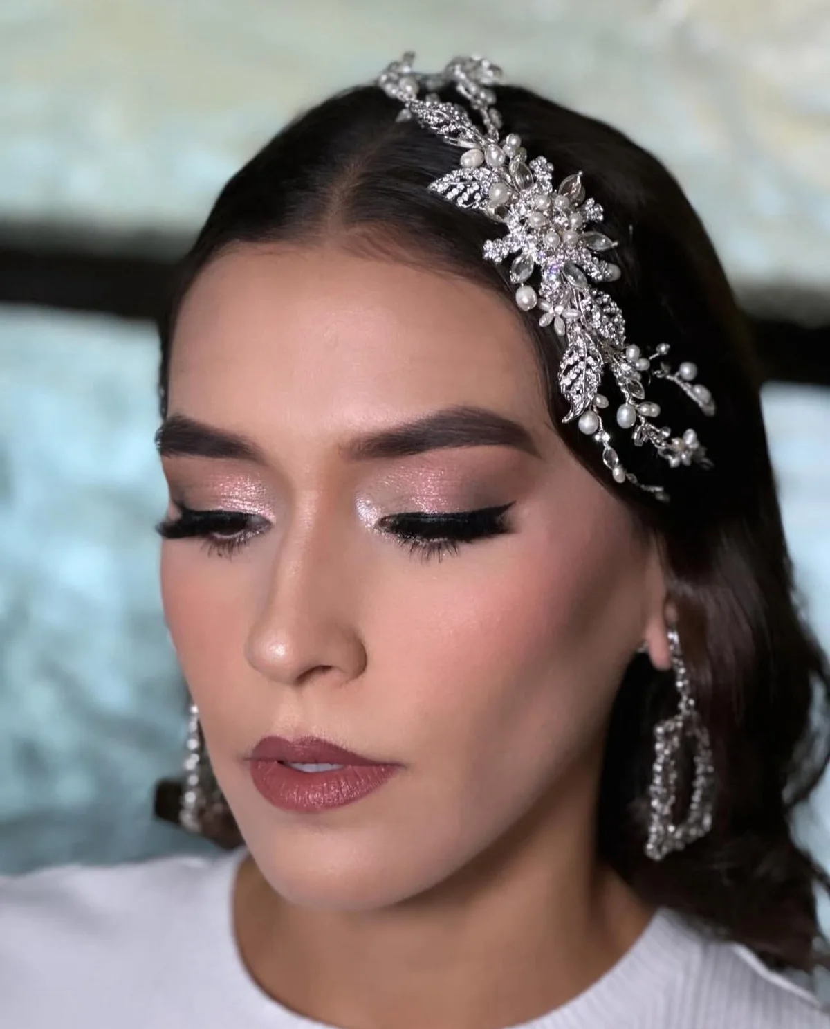 Novia con tocado de cristales y perlas, maquillaje glam en tonos rosados