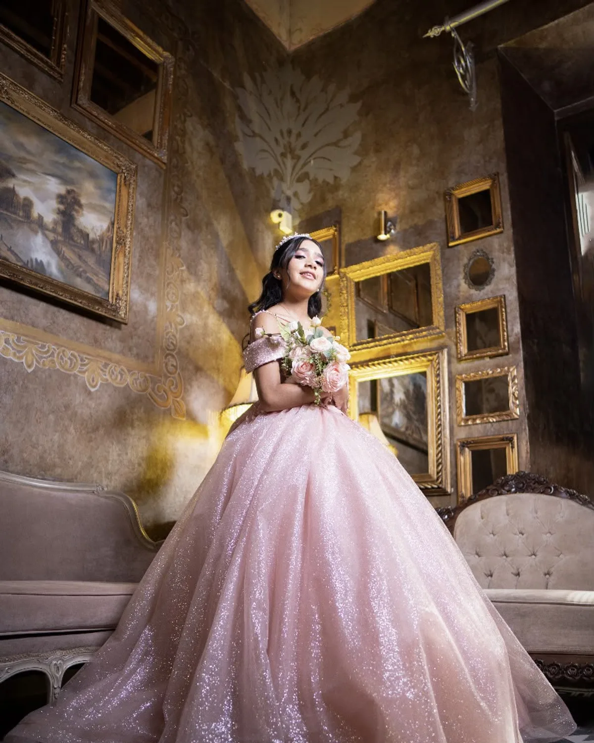 Quinceañera con vestido rosa de glitter y ramo en salón vintage